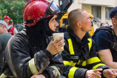 Kharkiv, Ukrayna, 7 Haziran 2025. İtfaiyeciler, Harkiv 'deki bir yerleşim yerine yapılan Rus saldırısından sonra dinleniyorlar. Birçok apartman yangını ve pencerenin tahrip olmasıyla hasar büyük..