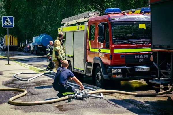 Kharkiv, Ukrayna, 7 Haziran 2025, Harkiv 'deki hasarlı binanın yakınına itfaiye araçları park edilmiştir. Hasar büyük, birkaç apartman yanıyor ve birçok pencere yıkıldı..