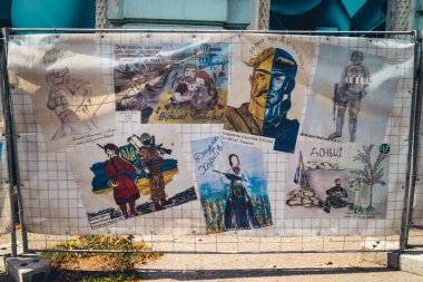 Kharkiv, Ukrayna, 27 Ağustos 2025. Savaş felaketlerini resmeden çocukların çizimleri, Rus füze saldırısının ardından hasar gören bir binanın çalışmalarını gizleyen brandalara basılmıştır..