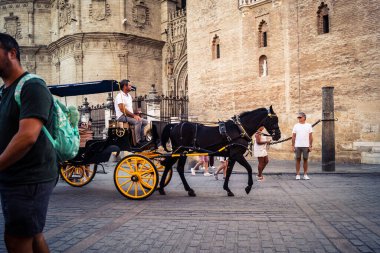 Seville, İspanya, 21 Eylül 2025. Atlı turistler Sevilla şehir merkezinin tarihi bölgesini ziyaret ediyor ve dar, pitoresk caddelerde yürüyor..