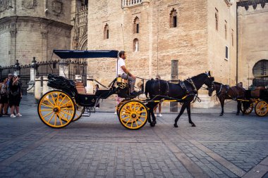Seville, İspanya, 21 Eylül 2025. Atlı turistler Sevilla şehir merkezinin tarihi bölgesini ziyaret ediyor ve dar, pitoresk caddelerde yürüyor..