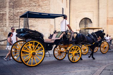 Seville, İspanya, 21 Eylül 2025. Atlı turistler Sevilla şehir merkezinin tarihi bölgesini ziyaret ediyor ve dar, pitoresk caddelerde yürüyor..