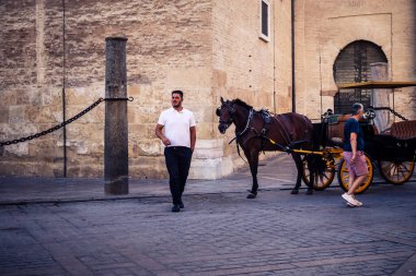 Seville, İspanya, 21 Eylül 2025. Atlı turistler Sevilla şehir merkezinin tarihi bölgesini ziyaret ediyor ve dar, pitoresk caddelerde yürüyor..