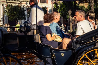 Seville, İspanya, 21 Eylül 2025. Atlı turistler Sevilla şehir merkezinin tarihi bölgesini ziyaret ediyor ve dar, pitoresk caddelerde yürüyor..