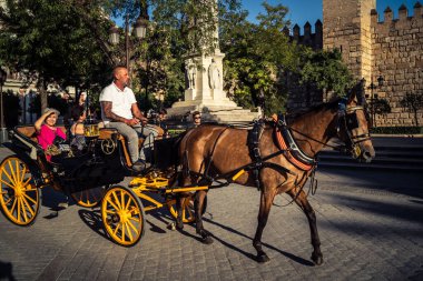 Seville, İspanya, 21 Eylül 2025. Atlı turistler Sevilla şehir merkezinin tarihi bölgesini ziyaret ediyor ve dar, pitoresk caddelerde yürüyor..