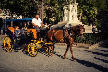 Seville, İspanya, 21 Eylül 2025. Atlı turistler Sevilla şehir merkezinin tarihi bölgesini ziyaret ediyor ve dar, pitoresk caddelerde yürüyor..