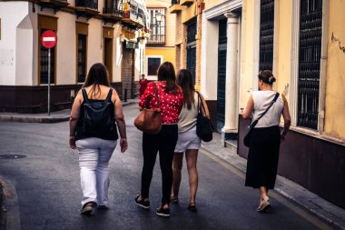 Seville, İspanya, 21 Eylül 2025 Sevilla şehir merkezinin tarihi bölgesini ziyaret eden turistler dar, pitoresk caddelerde yürüyorlar..