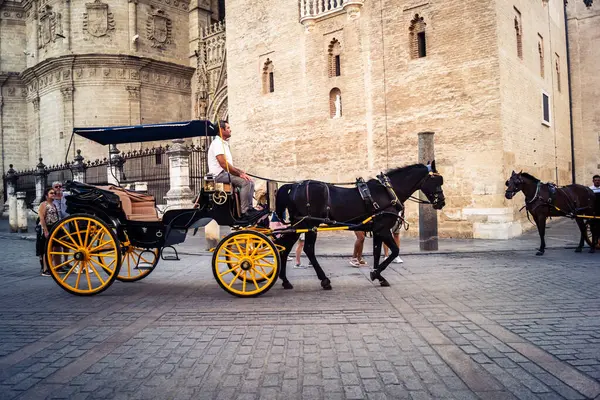 Seville, İspanya, 21 Eylül 2025. Atlı turistler Sevilla şehir merkezinin tarihi bölgesini ziyaret ediyor ve dar, pitoresk caddelerde yürüyor..