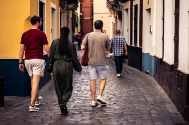 Seville, İspanya, 21 Eylül 2025 Sevilla şehir merkezinin tarihi bölgesini ziyaret eden turistler dar, pitoresk caddelerde yürüyorlar..