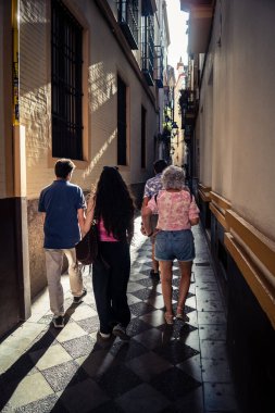 Seville, İspanya, 21 Eylül 2025 Sevilla şehir merkezinin tarihi bölgesini ziyaret eden turistler dar, pitoresk caddelerde yürüyorlar..