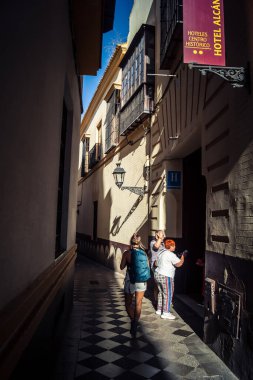 Seville, İspanya, 21 Eylül 2025 Sevilla şehir merkezinin tarihi bölgesini ziyaret eden turistler dar, pitoresk caddelerde yürüyorlar..