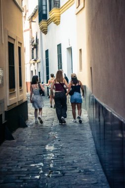 Seville, İspanya, 21 Eylül 2025 Sevilla şehir merkezinin tarihi bölgesini ziyaret eden turistler dar, pitoresk caddelerde yürüyorlar..