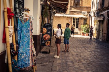 Seville, İspanya, 21 Eylül 2025 Sevilla şehir merkezinin tarihi bölgesini ziyaret eden turistler dar, pitoresk caddelerde yürüyorlar..