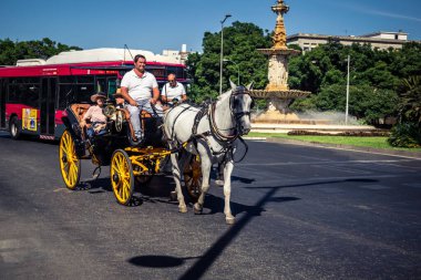 Seville, İspanya, 21 Eylül 2025. Atlı turistler Sevilla şehir merkezinin tarihi bölgesini ziyaret ediyor ve dar, pitoresk caddelerde yürüyor..