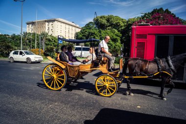 Seville, İspanya, 21 Eylül 2025. Atlı turistler Sevilla şehir merkezinin tarihi bölgesini ziyaret ediyor ve dar, pitoresk caddelerde yürüyor..