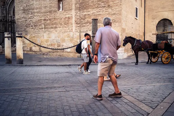 Seville, İspanya, 21 Eylül 2025 Sevilla şehir merkezinin tarihi bölgesini ziyaret eden turistler dar, pitoresk caddelerde yürüyorlar..