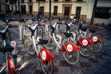 Seville, İspanya, 21 Eylül 2025 Sevilla 'nın tarihi şehir merkezinde, dar, pitoresk caddelerden kiralamak için bisiklet.