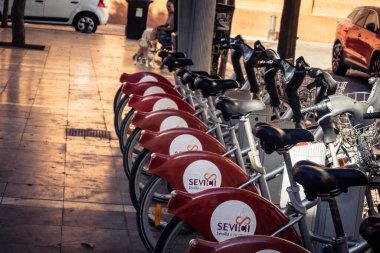 Seville, İspanya, 21 Eylül 2025 Sevilla 'nın tarihi şehir merkezinde, dar, pitoresk caddelerden kiralamak için bisiklet.