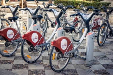 Seville, İspanya, 21 Eylül 2025 Sevilla 'nın tarihi şehir merkezinde, dar, pitoresk caddelerden kiralamak için bisiklet.