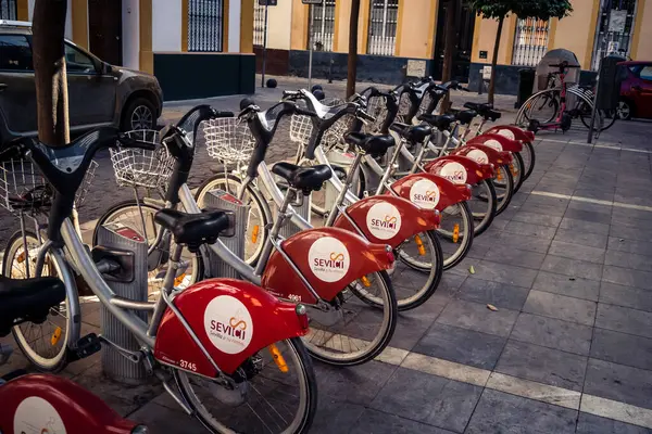 Seville, İspanya, 21 Eylül 2025 Sevilla 'nın tarihi şehir merkezinde, dar, pitoresk caddelerden kiralamak için bisiklet.