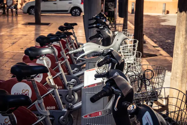 Seville, İspanya, 21 Eylül 2025 Sevilla 'nın tarihi şehir merkezinde, dar, pitoresk caddelerden kiralamak için bisiklet.