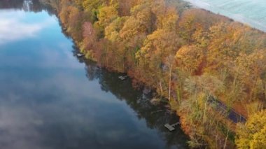 Göl, köy yolu, kırmızı yapraklı ağaçlar ve kar tozu ile altın sonbahar havasının güzel hava görüntüleri. Kırsal bölgedeki ilk kar yağışı. Kırsal alanlarda uçarken