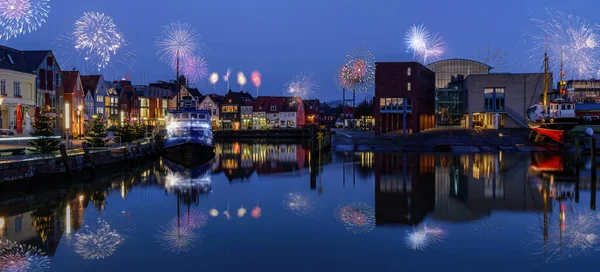 stock image New Year celebrations on New Years Eve with fireworks. Panorama view of festive lighting with firework romantic atmosphere in harbor of Husum at night.