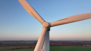 Rüzgâr türbininin dönen kanatlarını, arka planda konteynır gemisi ve eko tarlaları olan modern elektrik santralinin hava görüntülerini kapat. Yenilenebilir enerji..