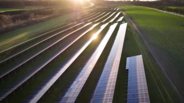 Aerial footage of photovoltaics on open spaces against sunset. The solar park along highway. View of a solar power station, Renewable green energy. Alternative energy sources. Clean energy industry. 