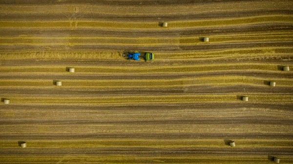 牵引机拉着圆圈的栏杆 从空中俯瞰着 机器卷起稻草 在农田上空吐出一个堆积如山的圆圈 拖拉机和农用机械镇流器的自顶向下视图 — 图库照片