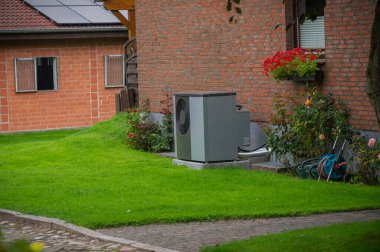 Air heat pump installed on the exterior facade of the old house. Sustainable heating solutions for old construction. Air source heat pump beside residential country cottage. clipart