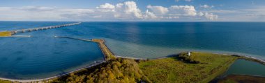 Danimarka kıyı şeridinden panoramik manzara. Deniz feneri Knudshoved ve Depo Köprüsü ufuktan ufka yayılarak iki kıyıya bağlanıyor. Uçsuz bucaksız denizin arka planına itilmiş deniz feneri