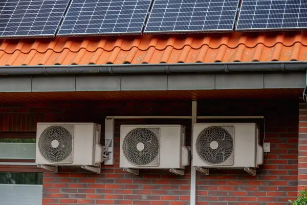 Solar panels on the roof and three air conditioner on the wall of a building. Solar panels on the roof and three digital inverter outdoor unit with refrigerant for cooling or heating operation.