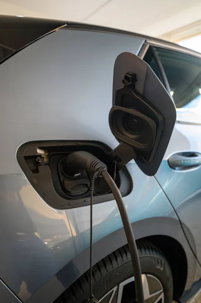 Close up of power supply cable plugged into an electric car being charged. Close-up of plug while charging an electric car. Close-up of charging cable of electrical device while charging the battery.