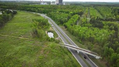  Otobanda kameralı hava görüntüleri var. Sonra bir dizi elektrik direği ve bacalardan yükselen buharın bulunduğu nükleer enerji santralini ortaya çıkarıyor..