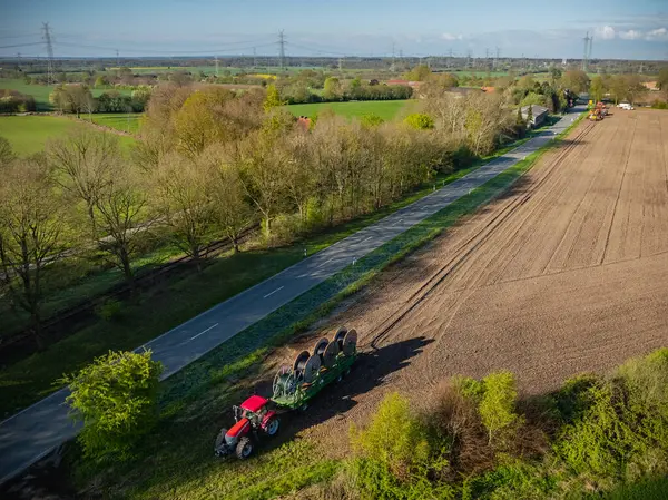 stock image Tractor pulling a trailer with four wire spools, cable drums. Deploying cables or wires over larger distances. Installing optical fiber cables along trench. Rolling out fiber optic cables for network