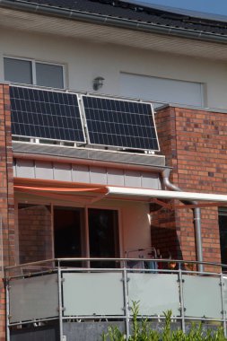 Balkon parmaklıklarında ve çatıda güneş panelleri olan modern bir yerleşim yeri. Balkondaki güneş panelleri, yenilenebilir enerji kaynaklarının karbon ayak izini azaltmak için kentsel tasarıma entegre edilmesi yaklaşımı.