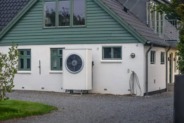 stock image Air heat pump installed on the exterior facade of newly renovated house.Sustainable heating solutions for newly renovated construction. Air source heat pump beside residential country cottage. 