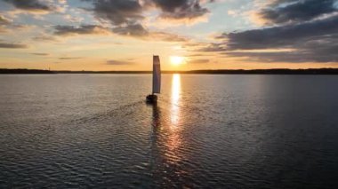 Gün batımında Flensburg fiyortunun sakin sularında süzülen beyaz yelkenli görüntüsü, batan güneşin sıcak ışınlarıyla aydınlatılıyor..