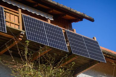 Kırsal ahşap bir balkona kurulmuş güneş panelleri, modern verimliliği geleneksel mimariyle birleştirerek sürdürülebilir enerji sağlıyor..