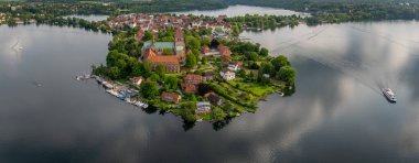 Ratzeburgs, Almanya 'nın kuzeyindeki eski bir adada katedral ve kırmızı çatılı evler ile, kamera sağdan sola dönerek tarihi kenti, göl manzarasını ve yelkenli teknesini gösteriyor.. 