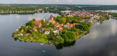 Ratzeburgs, Almanya 'nın kuzeyindeki eski bir adada katedral ve kırmızı çatılı evler ile, kamera sağdan sola dönerek tarihi kenti, göl manzarasını ve yelkenli teknesini gösteriyor.. 