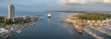 Travemnde 'nin hava manzarası, Lbeck' in kıyı bölgesi, Trave nehri girişi feribot dolu, yat dolu marina, modern rıhtım daireleri, oteller, tarihi uzun gemi ve geniş kumlu sahil girişi.. 