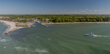 Niendorf 'un Baltık sahil limanı manzarası. Limanın girişinde gezinen gemi kumlu plajlarla çevrili seyir şamandıraları, yatla dolu limanı koruyan taştan dalgakıranlar..