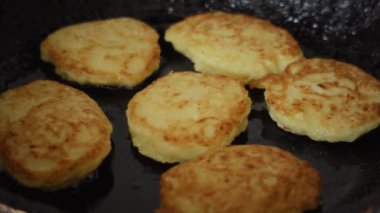 Close-up of golden homemade zucchini fritters sizzling in a frying pan on a stovetop. High quality 4k footage