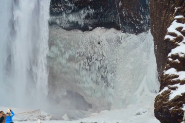 Buz gibi yüzeyi ve karla kaplı kayaları olan donmuş şelale doğanın kış güzelliğini gözler önüne seriyor. Konum: Skogafoss Şelalesi İzlanda.