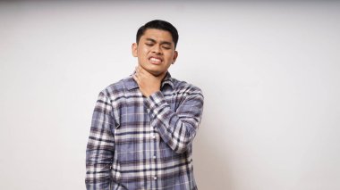 Genç Asyalı adamın boğazına dokunması beyaz arka planda acı ifadesini gösteriyor. Stüdyo çekimi