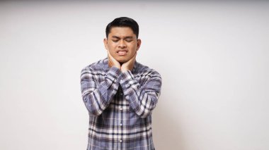 Genç Asyalı adamın boğazına dokunması beyaz arka planda acı ifadesini gösteriyor. Stüdyo çekimi