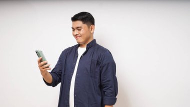 Cep telefonu tutan genç Asyalı adam coşkulu bir ifade sergiliyor