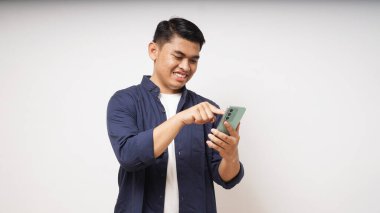 Cep telefonu tutan genç Asyalı adam coşkulu bir ifade sergiliyor